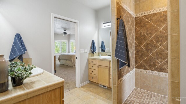 bathroom featuring tile patterned floors, vanity, ensuite bathroom, ceiling fan, and a tile shower