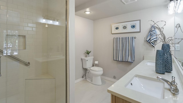 bathroom featuring toilet, double vanity, a tile shower, and baseboards