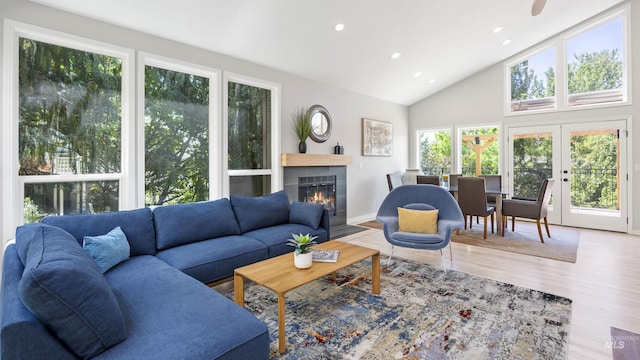 living room with wood finished floors, a tiled fireplace, recessed lighting, high vaulted ceiling, and french doors