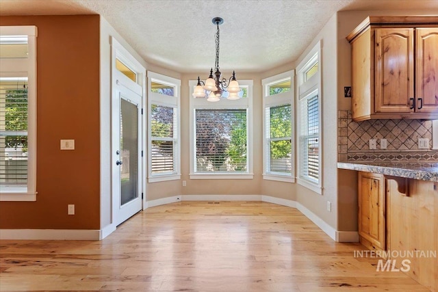 1112 W Belknap Dr, Nampa, ID 83686 - unfurnished dining area with a chandelier, light wood-style flooring, and a textured ceiling