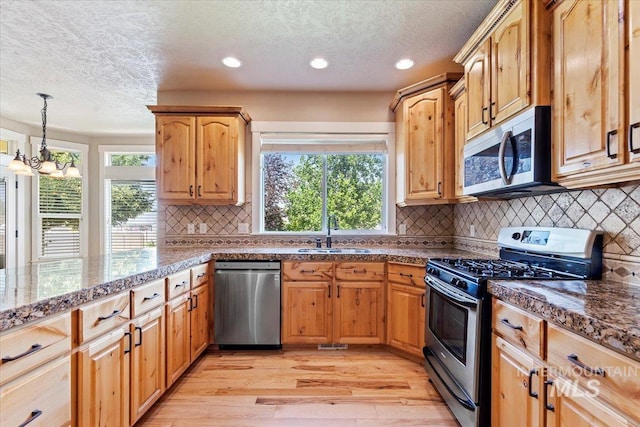 1112 W Belknap Dr, Nampa, ID 83686 - kitchen featuring appliances with stainless steel finishes, a textured ceiling, light wood-style floors, a chandelier, and decorative backsplash