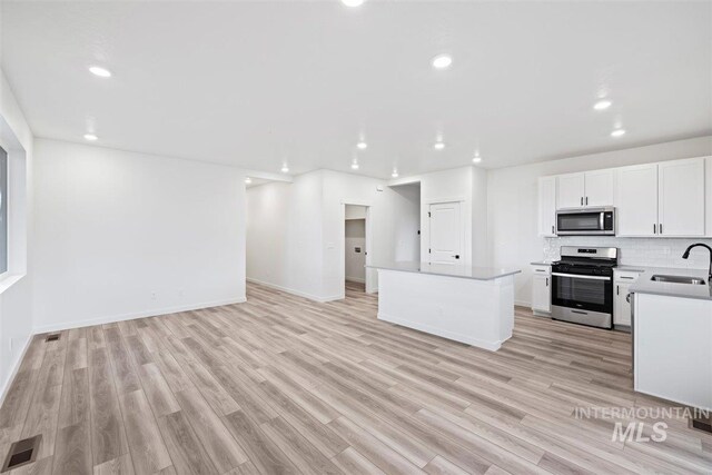 kitchen featuring stainless steel appliances, light hardwood / wood-style floors, sink, and a kitchen island