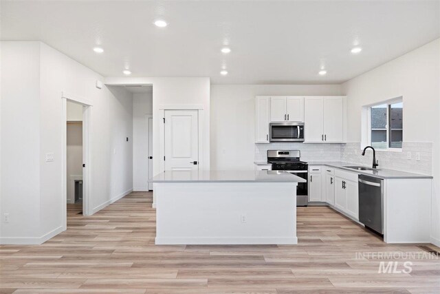 kitchen featuring white cabinets, sink, a kitchen island, and appliances with stainless steel finishes