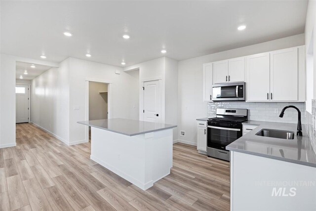 kitchen featuring light hardwood / wood-style floors, sink, a kitchen island, and appliances with stainless steel finishes