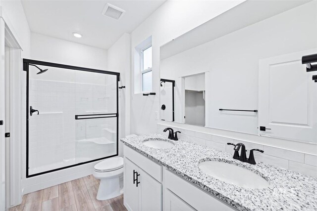 bathroom featuring a shower with door, vanity, decorative backsplash, hardwood / wood-style flooring, and toilet