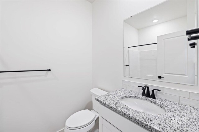 bathroom with toilet, tasteful backsplash, vanity, and a shower