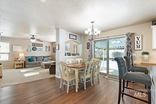 dining area with ceiling fan with notable chandelier, dark hardwood / wood-style floors, and a textured ceiling