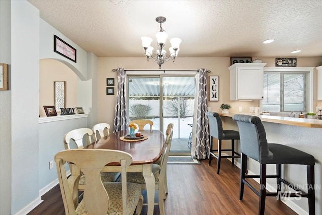 dining room featuring dark hardwood / wood-style flooring, a textured ceiling, and a chandelier