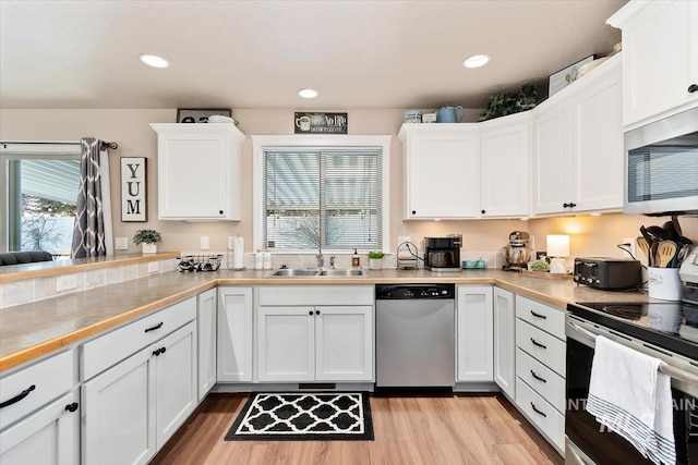 kitchen featuring appliances with stainless steel finishes, sink, white cabinets, and light hardwood / wood-style flooring