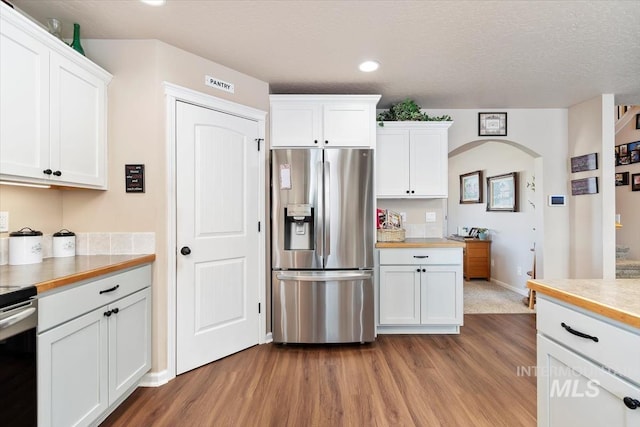 kitchen featuring white cabinetry, butcher block counters, stainless steel appliances, light hardwood / wood-style floors, and a textured ceiling