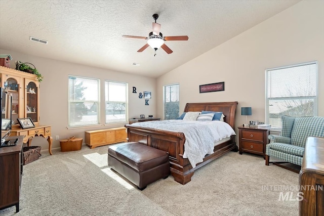 bedroom featuring ceiling fan, light colored carpet, vaulted ceiling, and a textured ceiling