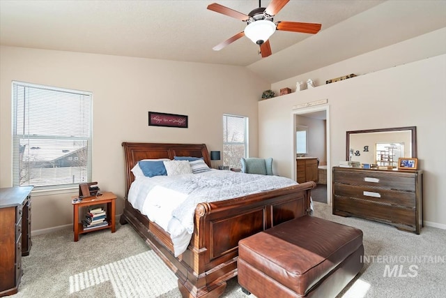 bedroom featuring connected bathroom, vaulted ceiling, light colored carpet, and ceiling fan