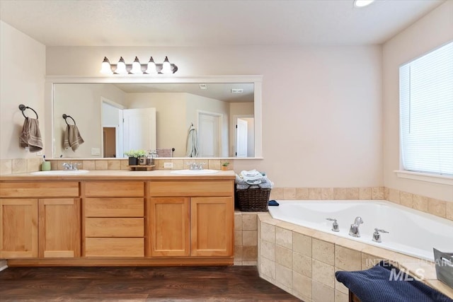 bathroom with vanity, hardwood / wood-style flooring, and tiled bath