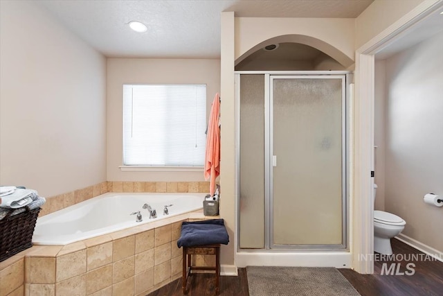 bathroom featuring independent shower and bath, hardwood / wood-style flooring, a textured ceiling, and toilet