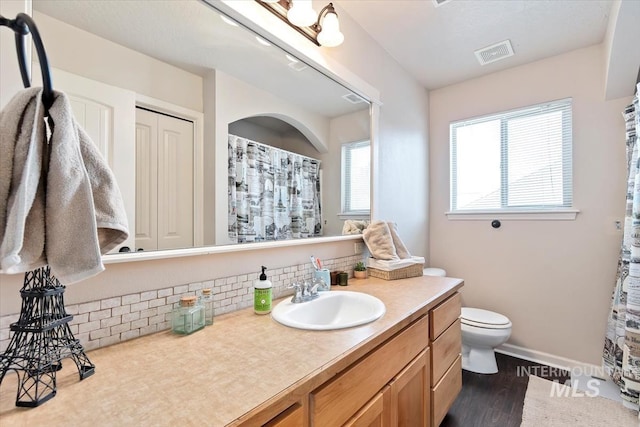 bathroom with decorative backsplash, vanity, toilet, and wood-type flooring