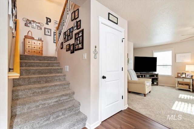 staircase featuring wood-type flooring and a textured ceiling