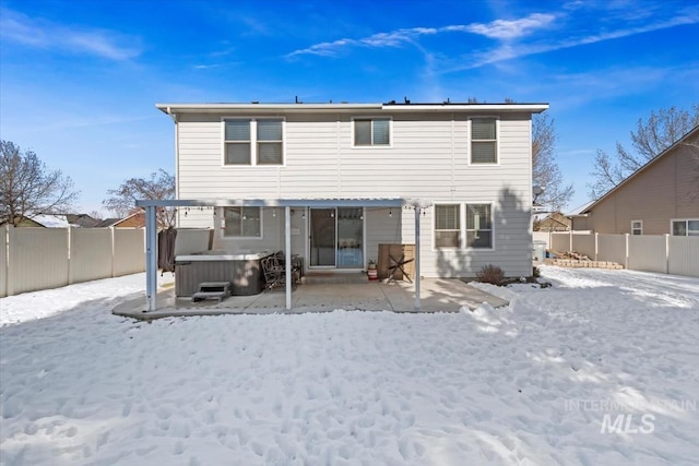 snow covered rear of property featuring a pergola and a hot tub