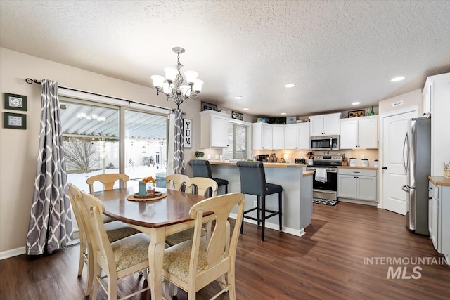 dining space featuring dark hardwood / wood-style flooring, a textured ceiling, and an inviting chandelier