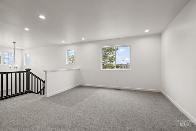 carpeted spare room with recessed lighting, a healthy amount of sunlight, baseboards, and an inviting chandelier