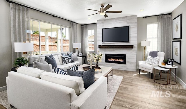 living room with a tile fireplace, plenty of natural light, wood finished floors, and baseboards