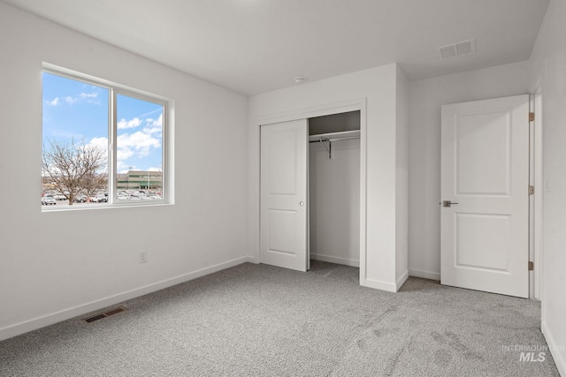 unfurnished bedroom featuring carpet, visible vents, a closet, and baseboards