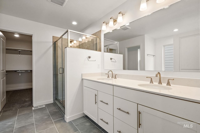 full bathroom with a spacious closet, visible vents, a stall shower, and a sink