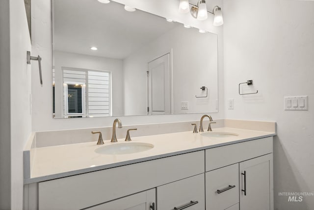full bath featuring double vanity, recessed lighting, and a sink