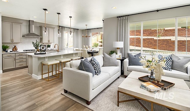 living room with recessed lighting, a notable chandelier, and light wood-style flooring