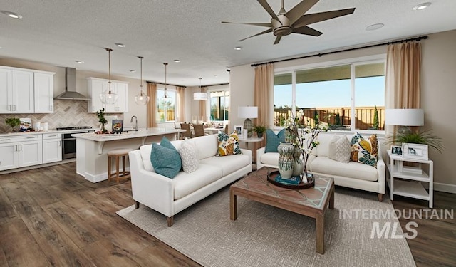 living room with a ceiling fan, baseboards, dark wood finished floors, recessed lighting, and a textured ceiling