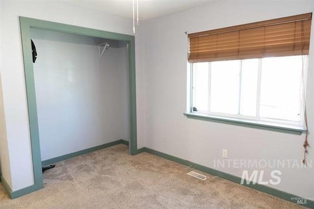 unfurnished bedroom featuring light carpet and a closet