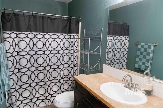 bathroom featuring a shower with shower curtain, vanity, and toilet