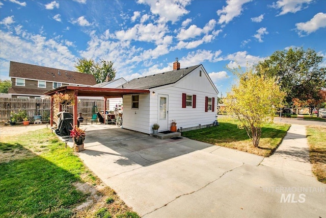 rear view of house featuring a carport and a yard