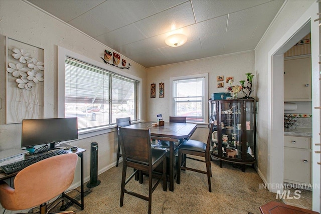 dining space featuring light colored carpet and crown molding