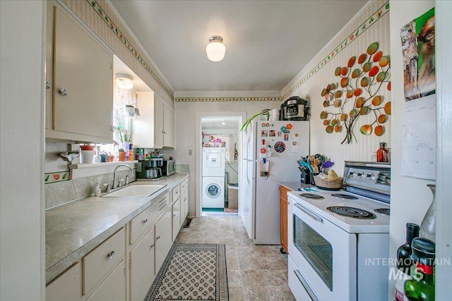 kitchen featuring white appliances, stacked washing maching and dryer, crown molding, and sink