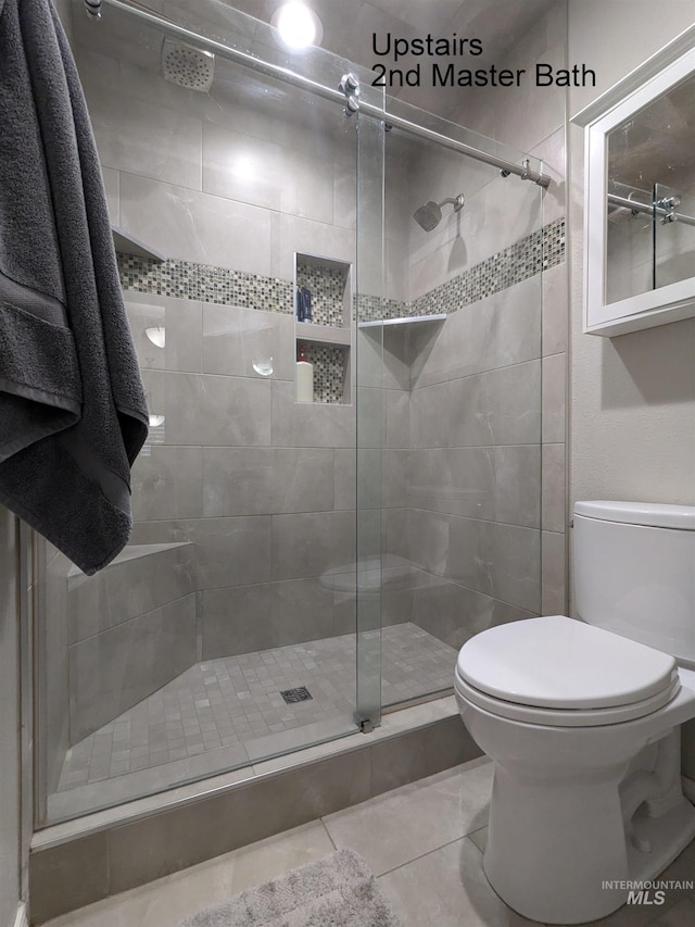 bathroom with tile patterned floors, toilet, and walk in shower