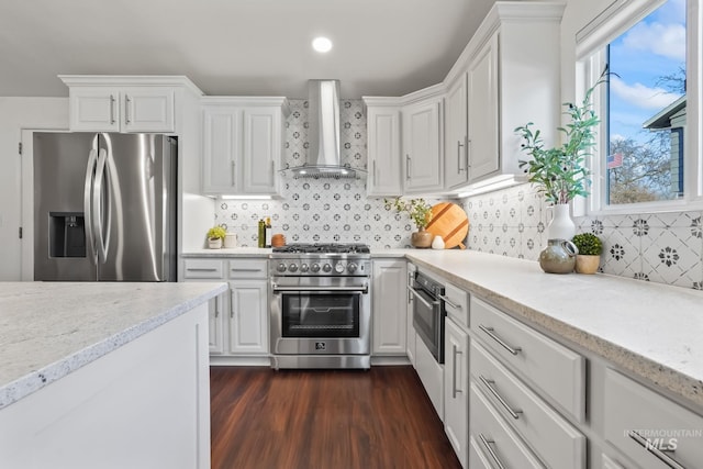 kitchen with white cabinetry, stainless steel appliances, wall chimney range hood, tasteful backsplash, and dark hardwood / wood-style floors