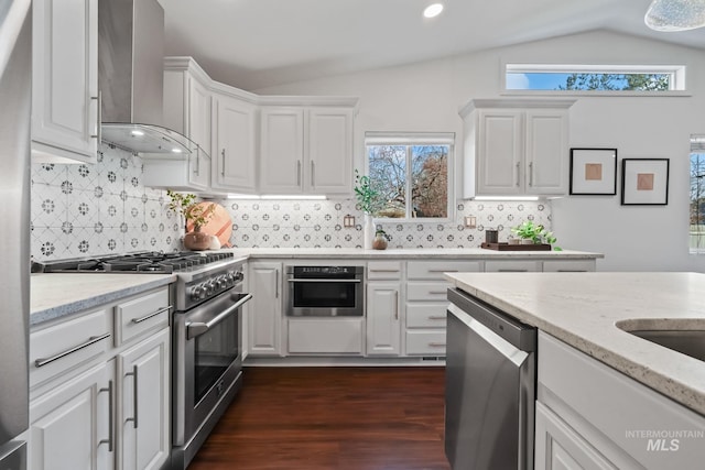 kitchen featuring white cabinets, appliances with stainless steel finishes, dark hardwood / wood-style floors, and wall chimney range hood