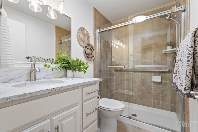 bathroom featuring tile patterned flooring, vanity, toilet, and an enclosed shower