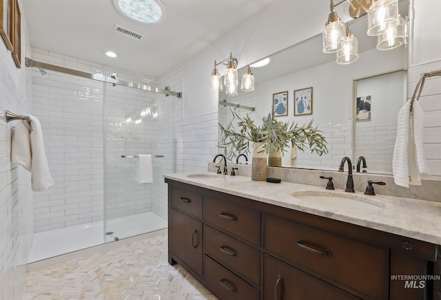 bathroom with vanity, a tile shower, and tile walls