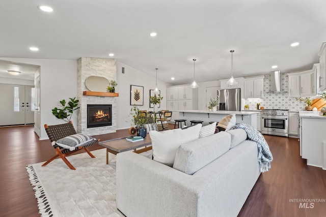 living room with a stone fireplace, light hardwood / wood-style flooring, and vaulted ceiling