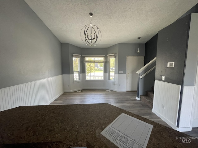 3915 N Abbott St, Caldwell, ID 83607 - unfurnished dining area featuring a chandelier, wood finished floors, stairway, a textured ceiling, and wainscoting