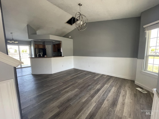 3915 N Abbott St, Caldwell, ID 83607 - unfurnished dining area with a chandelier, dark wood-style flooring, wainscoting, a textured ceiling, and vaulted ceiling