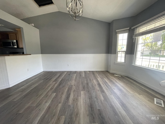 3915 N Abbott St, Caldwell, ID 83607 - empty room featuring dark wood-style floors, lofted ceiling, wainscoting, and a chandelier