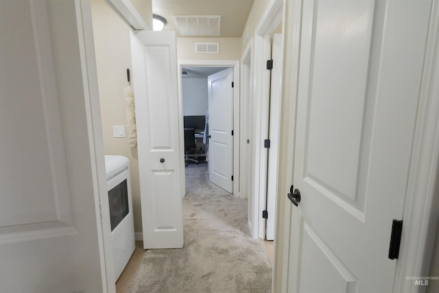 corridor featuring light colored carpet and washer / clothes dryer