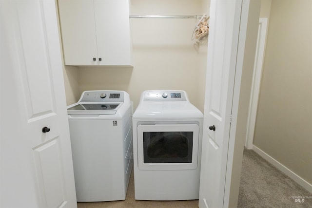 clothes washing area with cabinets, light colored carpet, and washing machine and dryer