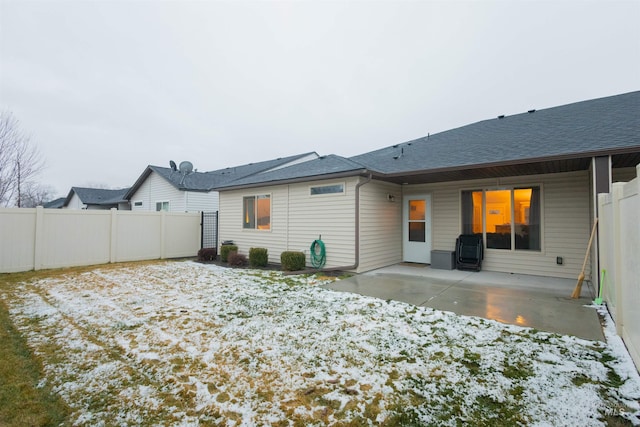 snow covered back of property with a patio