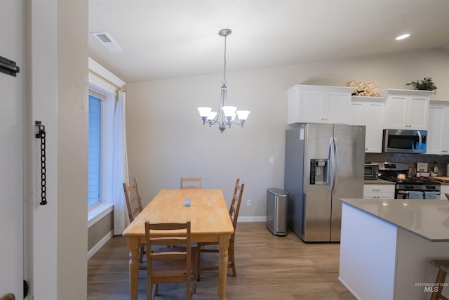 dining room with light hardwood / wood-style floors and a notable chandelier