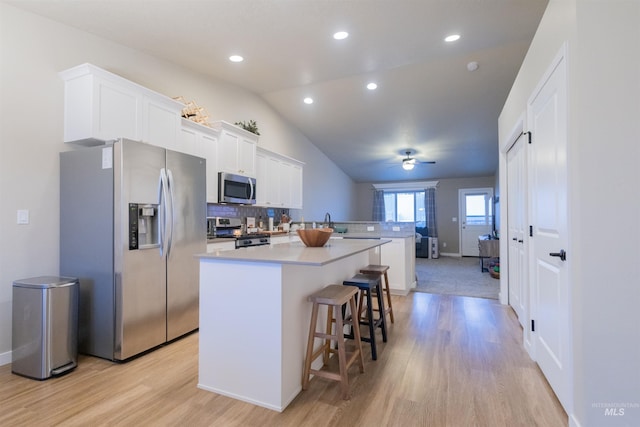 kitchen featuring white cabinets, a breakfast bar, a kitchen island, and stainless steel appliances