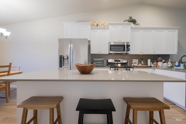 kitchen featuring tasteful backsplash, stainless steel appliances, sink, white cabinets, and a breakfast bar area