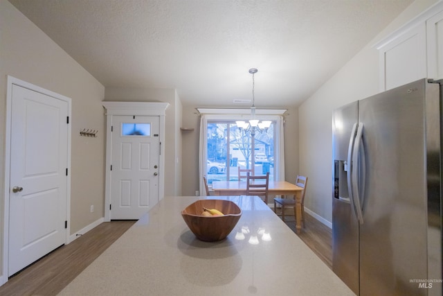 kitchen featuring dark hardwood / wood-style floors, a chandelier, decorative light fixtures, and stainless steel refrigerator with ice dispenser